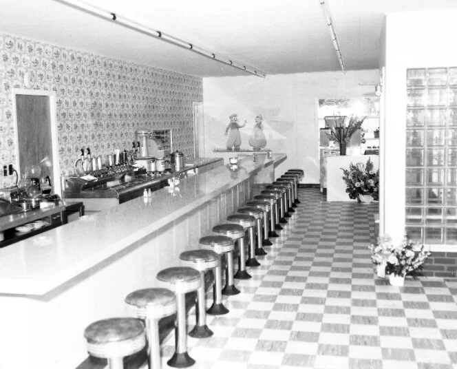 Black and white photo of the original diner counter with a long row of stools